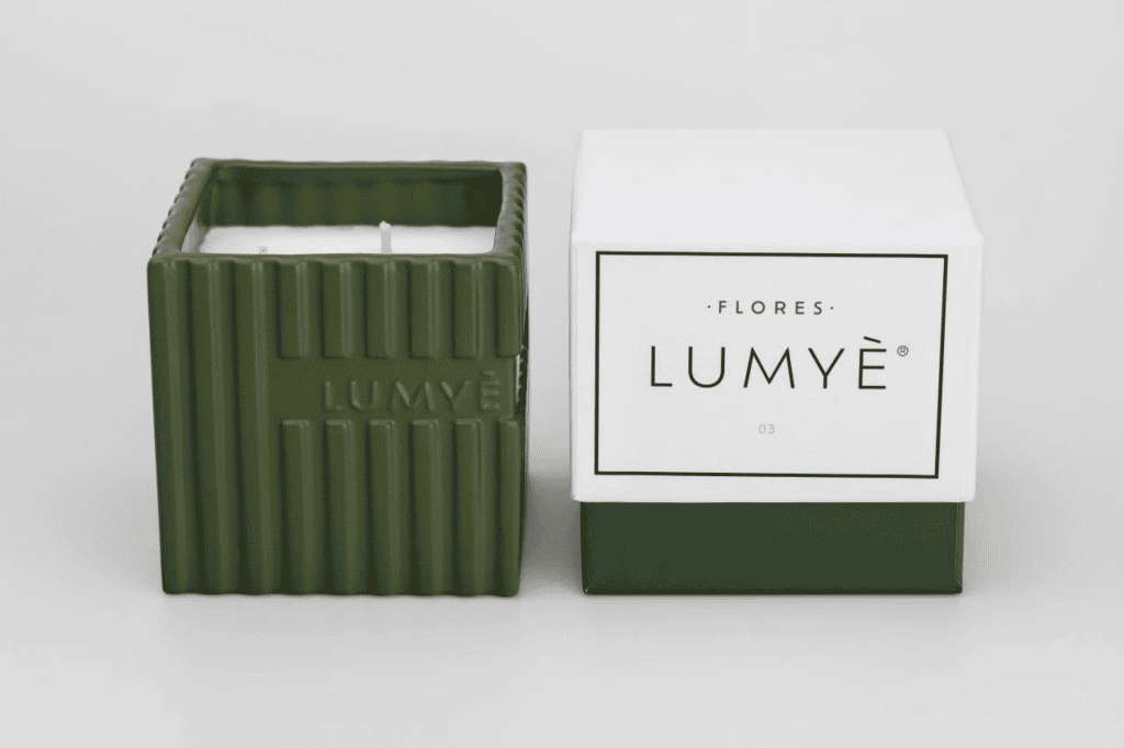 Zielona świeca Lumyè obok pudełka.