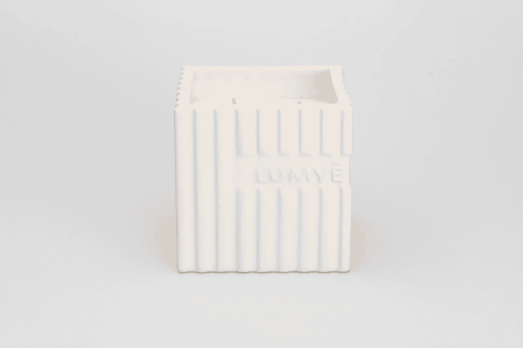 Białe ceramiczne pudełko z żłobieniami, minimalistyczny design.