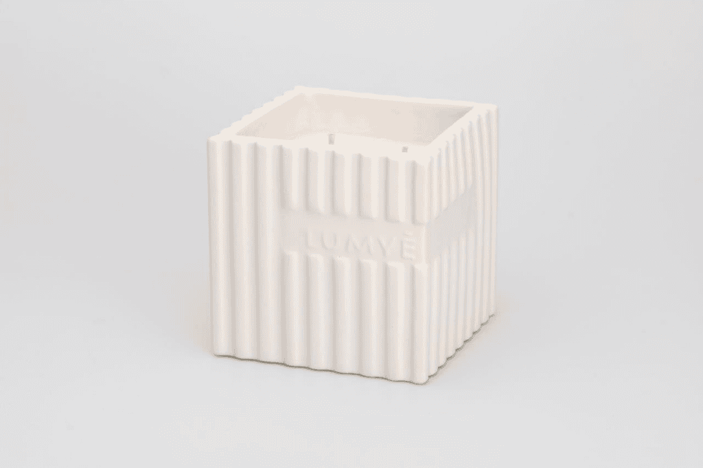 Biały ceramiczny kwadratowy wazon z żebrowanymi bokami.