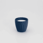 Granatowa świeca w ceramicznej osłonce.